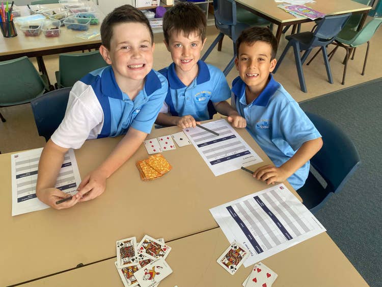 three students doing work at table smiling