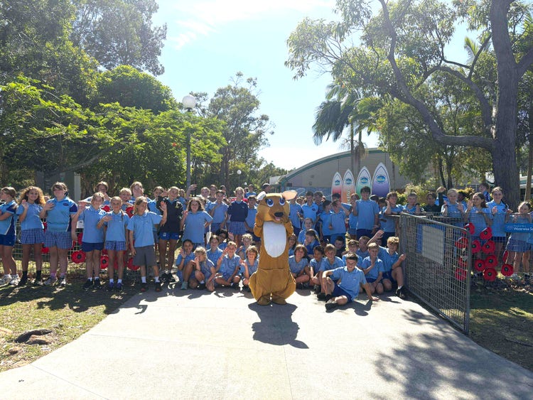 Photo of Clarry the school mascot in front of a big group of students at front of school