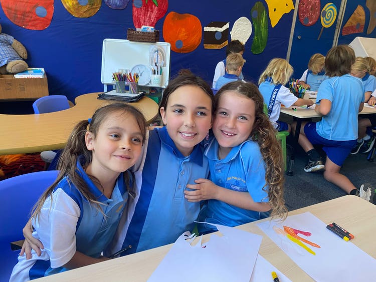 Three students smiling together in a classroom