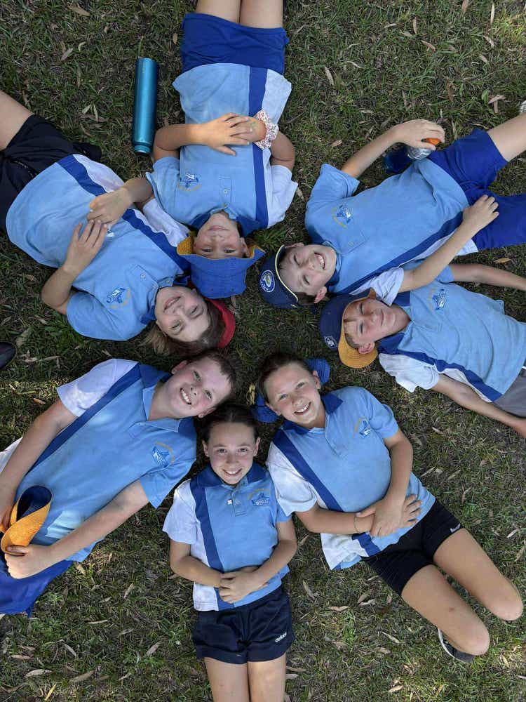 students lying on their back in a circle smiling