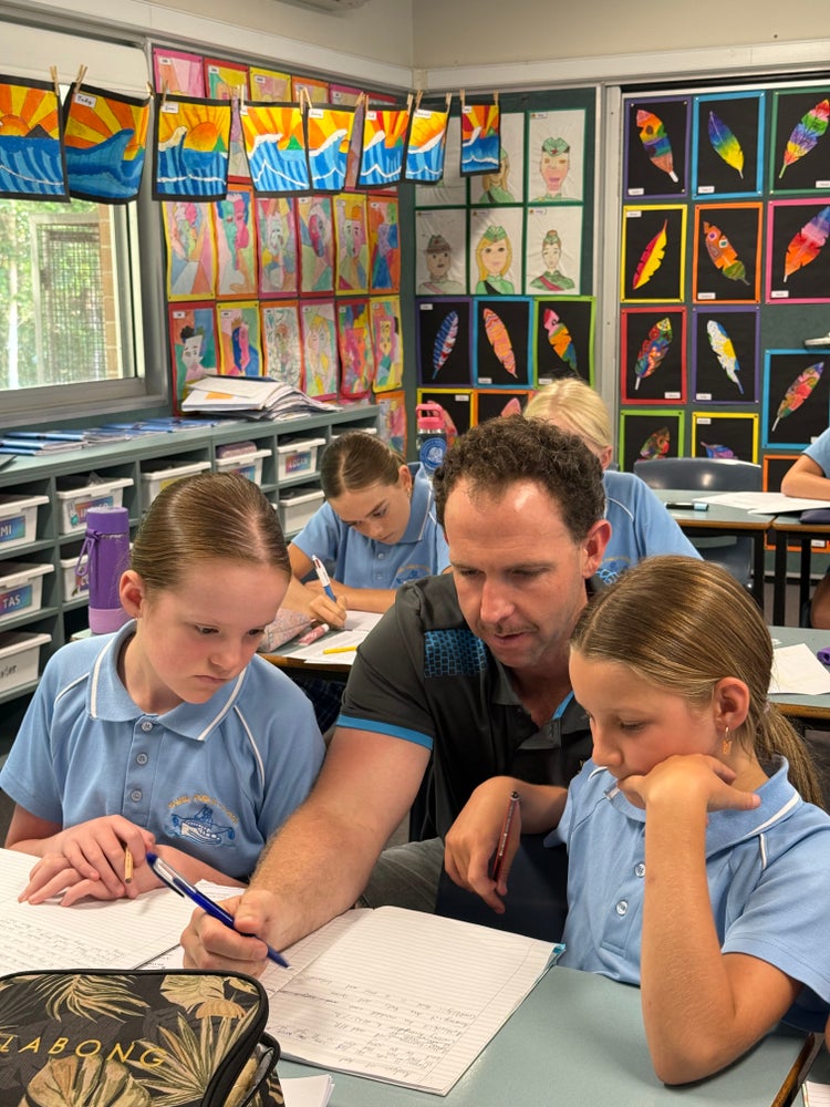 Teacher helping two students with their work