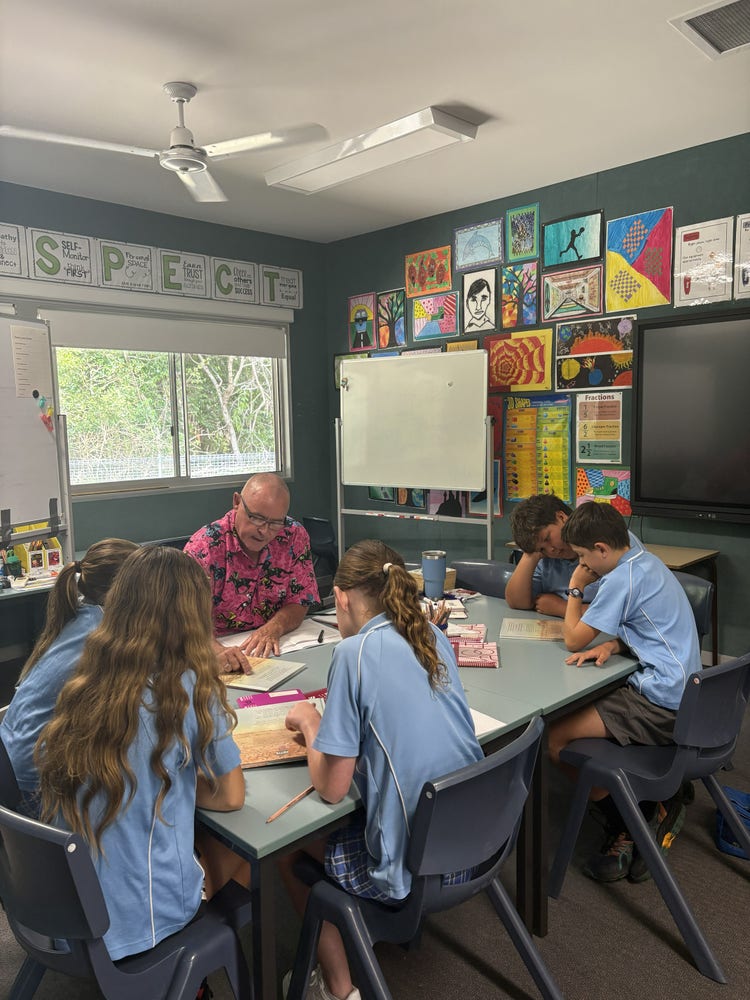 Photo of small class showing five students working at their desk with one teacher