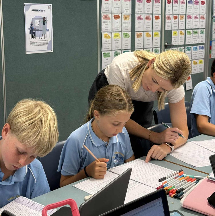 female teacher leaning down and helping a student