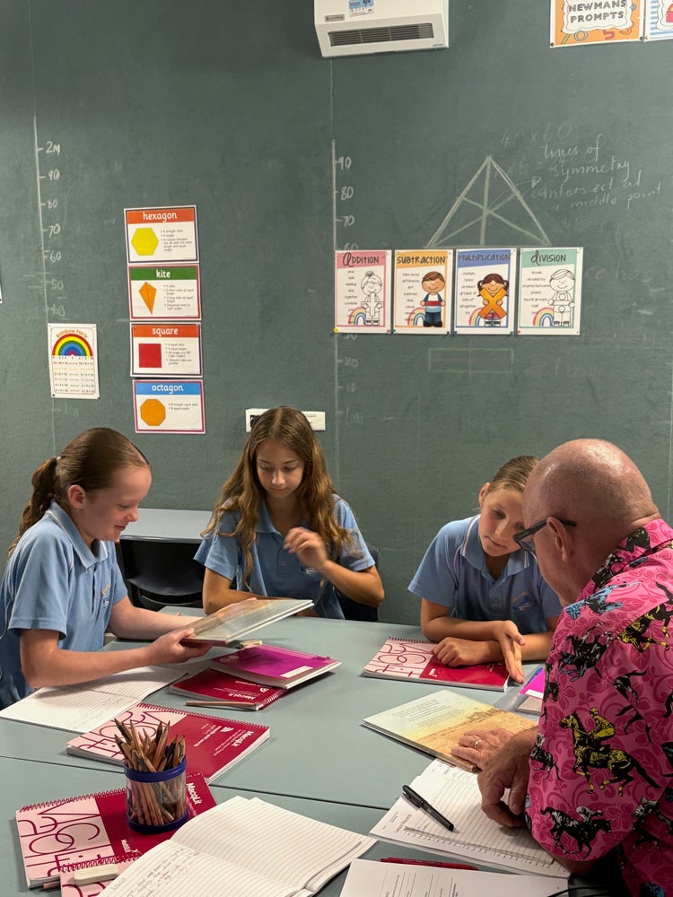 small class setting with teacher and three students at the desk