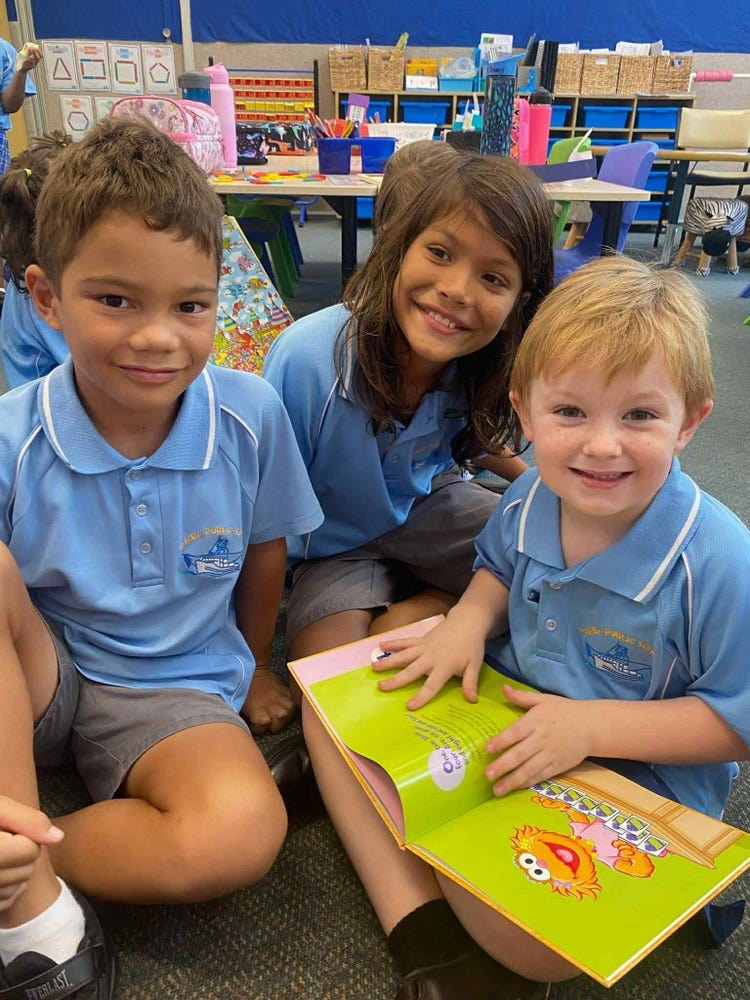 three students smiling reading a book